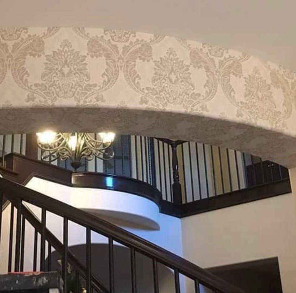 Curved staircase arch with floral damask wallpaper in dark charcoal tones