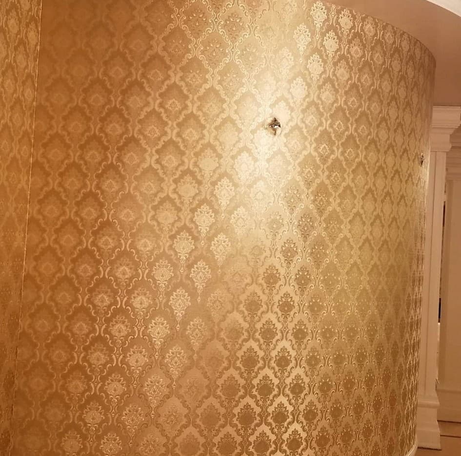 Curved interior wall covered in rich gold and bronze damask wallpaper pattern