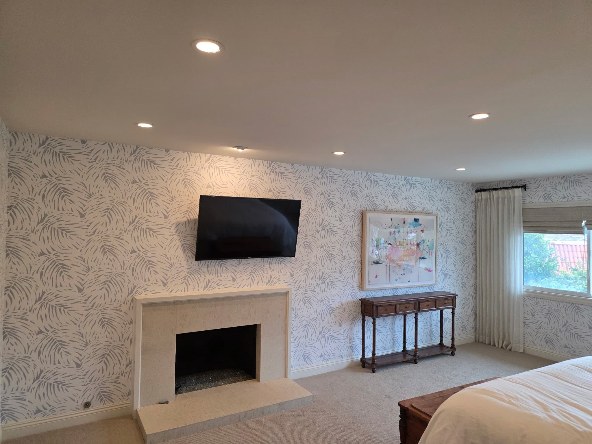 Bedroom with botanical leaf wallpaper, wall-mounted TV and marble fireplace