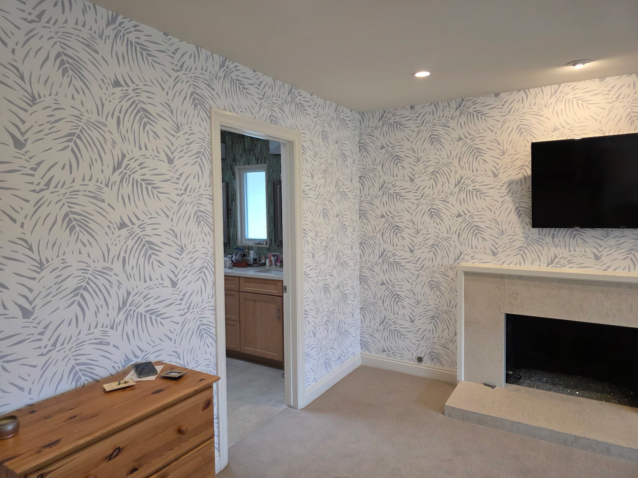 Corner view of bedroom showing botanical leaf wallpaper wrapping the entire room