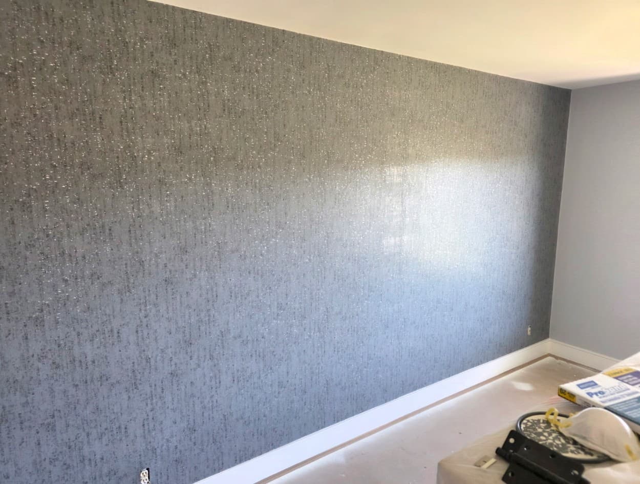 Silver metallic shimmer textured wallpaper covering a bedroom feature wall
