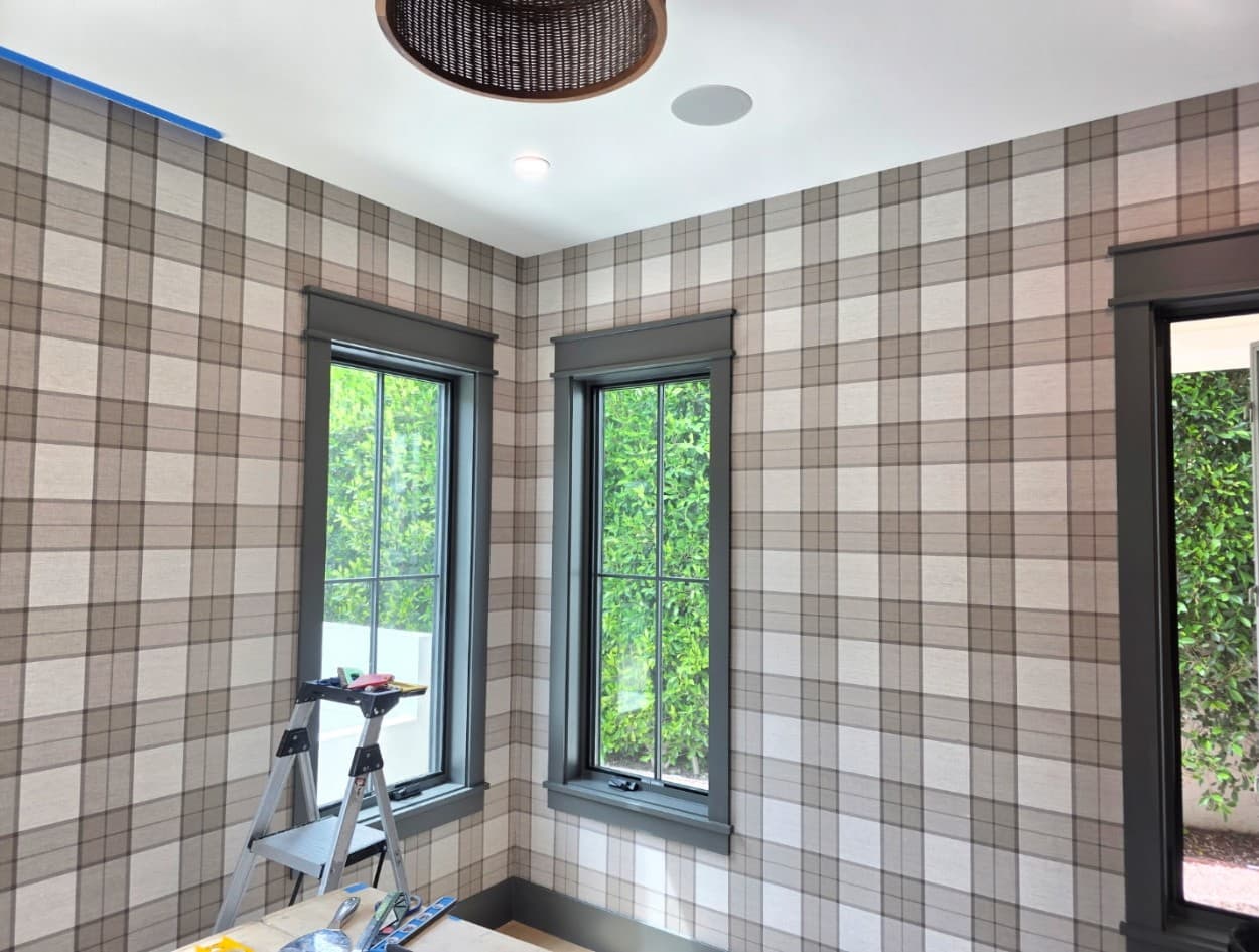 Plaid tartan pattern wallpaper wrapping a bright room with gray-trimmed windows