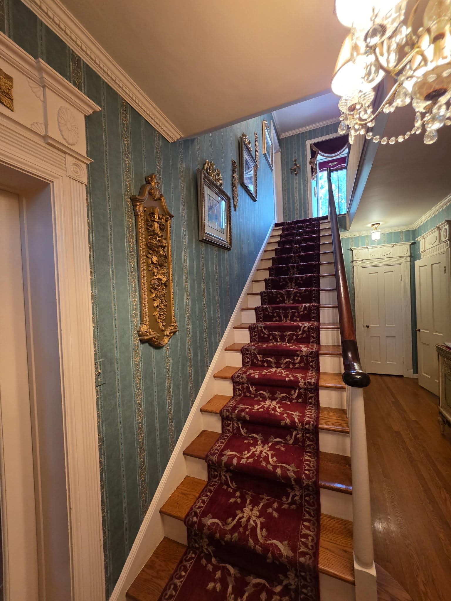 Elegant staircase hallway with luxury teal striped wallpaper and chandelier